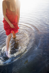 Woman in red dress standing in lake - FOLF06632
