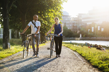 Man and woman walking with bicycles in city - FOLF06681