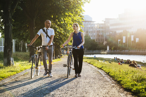 Mann und Frau zu Fuß mit Fahrrädern in der Stadt - FOLF06681