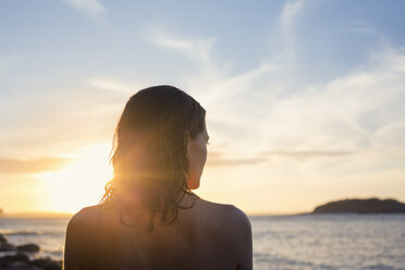 Rückansicht einer Frau mit Blick aufs Meer bei Sonnenuntergang - FOLF06690