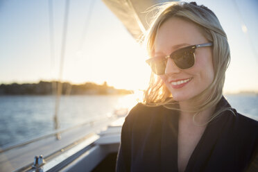 Smiling woman in sunglasses on boat at sunset - FOLF06692