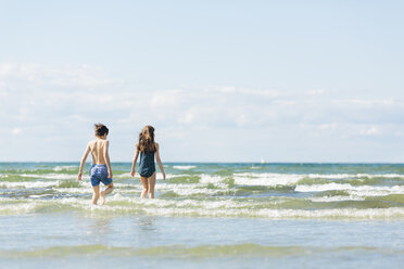 Girl and boy walking into sea - FOLF06716