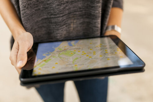 Close-up of woman holding tablet with digital street map - VABF01526