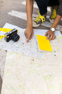 Close-up of woman with camera searching on city map - VABF01541