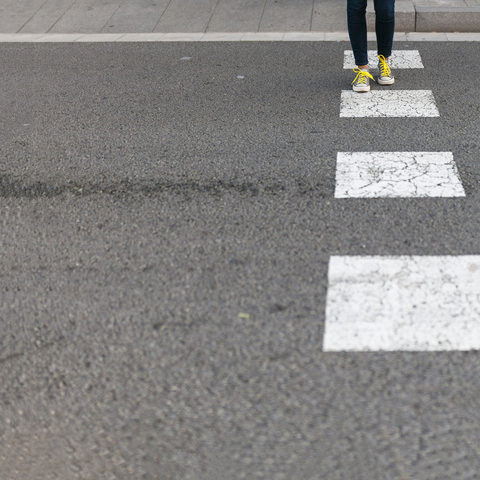 Close-up of woman wearing sneakers crossing street stock photo