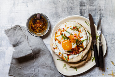 Fladenbrot mit Knoblauchjoghurt, Spiegelei und Chilibutter auf Schneidebrett - SBDF03509