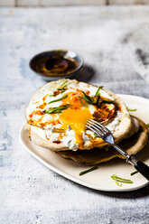 Fladenbrot mit Knoblauchjoghurt, Spiegelei und Chilibutter auf Schneidebrett - SBDF03510