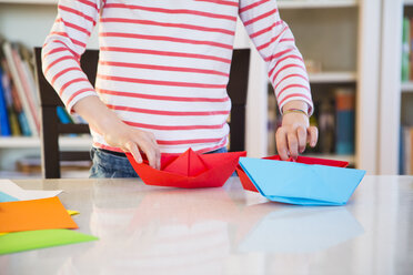 Close-up of girl tinkering with paper on table at home - LVF06859