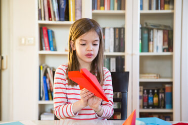 Girl tinkering paper plane on table at home - LVF06860