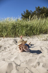 Boy in straw hat lying on beach - FOLF06978