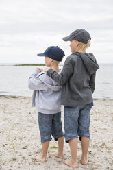Jungen mit Baseballmützen stehen am Strand - FOLF06984
