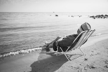 Älterer Mann sitzt auf einem Liegestuhl am Meer - FOLF06990