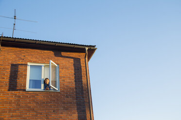 Junge schaut durch das Fenster eines Backsteinhauses - FOLF07015