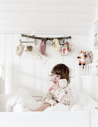 Kleines Mädchen, das im Bett sitzt und eine Puppe umarmt - FOLF07024
