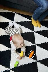 Kleiner Junge liegt auf Teppich und spielt mit Spielzeug - FOLF07125