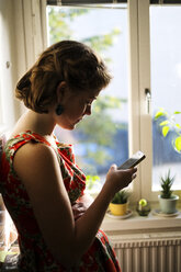 Junge Frau schreibt eine SMS auf einem Smartphone - FOLF07141