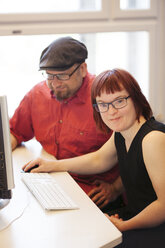 Woman with down syndrome working at computer with colleague - FOLF07226