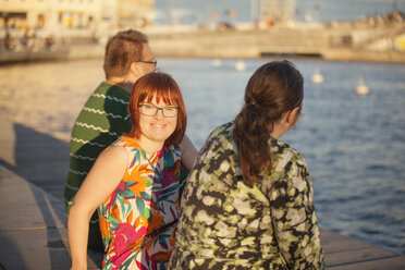 Frau mit Down-Syndrom sitzt mit Freunden auf der Promenade - FOLF07235
