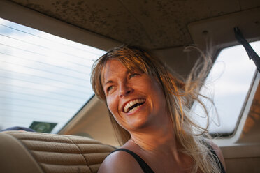 Blonde Frau lachend auf dem Rücksitz eines Autos - FOLF07254