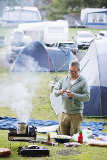 Älterer Mann beim Kochen auf dem Campingplatz - FOLF07301