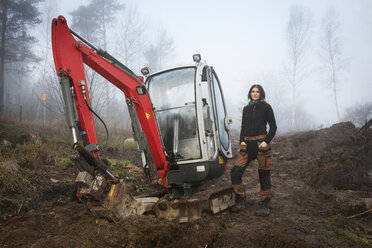 Frau steht bei Bulldozer im Wald - FOLF07457