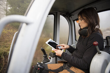 Frau benutzt digitales Tablet in Bulldozer - FOLF07460