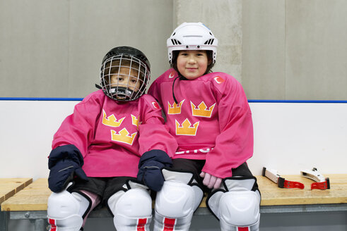 Mädchen in Eishockeykleidung sitzen auf einer Bank - FOLF07514