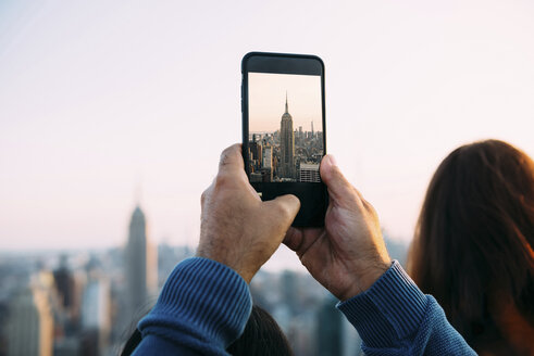 USA, New York City, Männerhände beim Fotografieren des Empire State Building mit dem Smartphone - GEMF01910