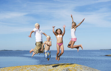 Gruppe von Kindern, die an einem sonnigen Tag am Strand springen - FOLF07562