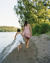 Two barefoot girls walking by sea - FOLF07563