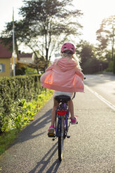 Mädchen mit rosa Helm fährt mit dem Fahrrad die Straße entlang - FOLF07684