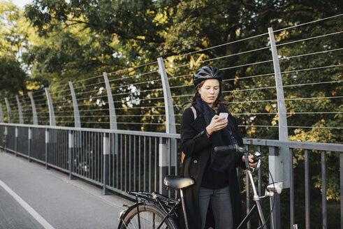 Junge Frau steht am Fahrrad und telefoniert - FOLF07699