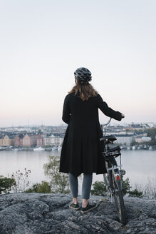 Rückansicht einer jungen Frau, die mit ihrem Fahrrad auf einem Felsen steht - FOLF07702