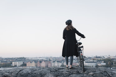 Rückansicht einer jungen Frau, die mit ihrem Fahrrad auf einem Felsen steht - FOLF07703