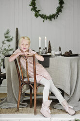 Young girl sitting on chair in living room during Christmas - FOLF07731