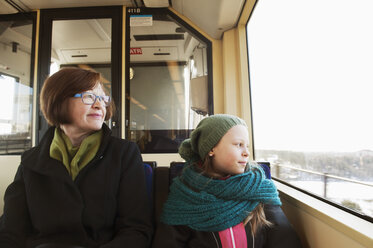 Mädchen sitzt mit Großmutter in der Straßenbahn und schaut durch das Fenster - FOLF07749