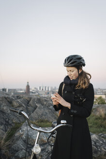 Junge Frau steht am Fahrrad und telefoniert - FOLF07755