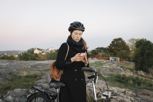 Junge Frau steht am Fahrrad und telefoniert - FOLF07756