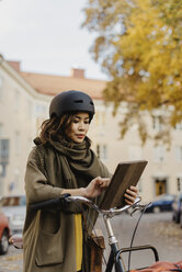 Junge Frau mit digitalem Tablet am Fahrrad stehend - FOLF07760