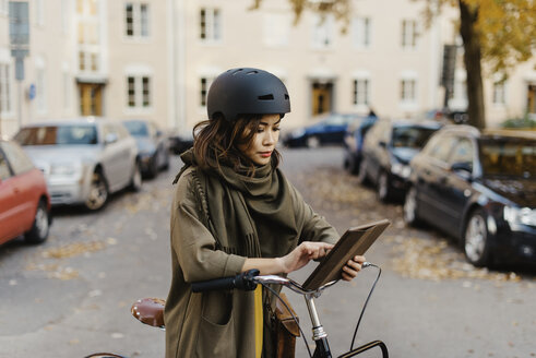 Junge Frau mit digitalem Tablet am Fahrrad stehend - FOLF07761