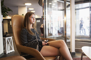 Teenager-Mädchen sitzt und hält Smartphone - FOLF07767