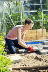 Mid adult woman paving in front of greenhouse - FOLF07799