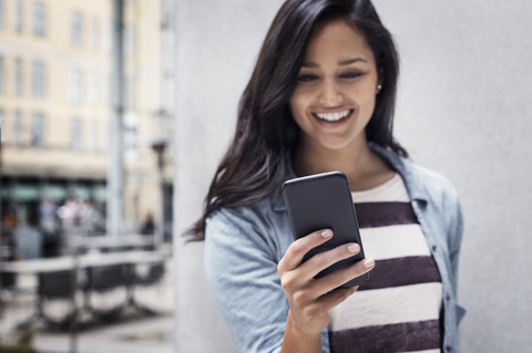 Junge Frau, die in der Stadt SMS schreibt, lizenzfreies Stockfoto