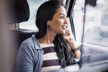 Junge Frau hört Musik im Taxi - CAVF33498