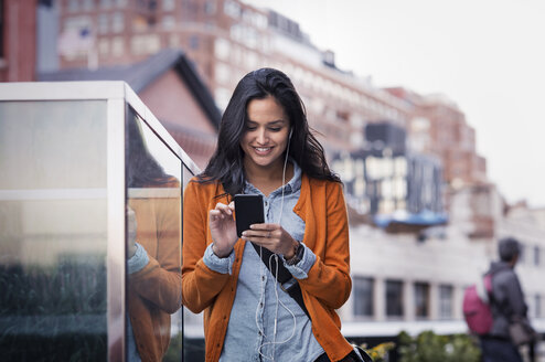 Junge Frau, die auf dem Gehweg eine SMS schreibt - CAVF33506