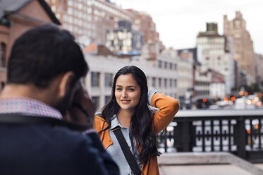 Couple taking pictures on footbridge in city - CAVF33508