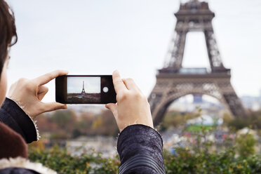 Junge Frau fotografiert den Eiffelturm mit ihrem Smartphone - CAVF33529