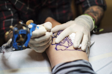 High angle view of man tattooing client at studio - CAVF33537