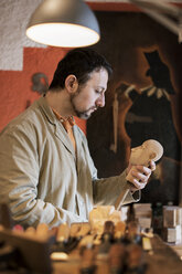 Man making wooden figurine in workshop - CAVF33542