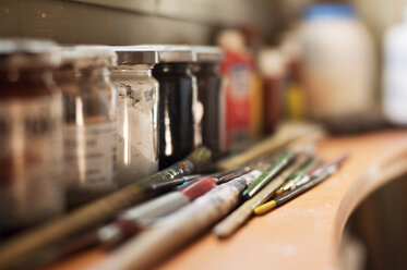 Nahaufnahme von Pinseln und Farben auf einem Tisch in einer Werkstatt - CAVF33543